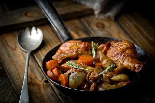 Primo piano di carne di pollo in padella con verdure poggiata su un tavolo