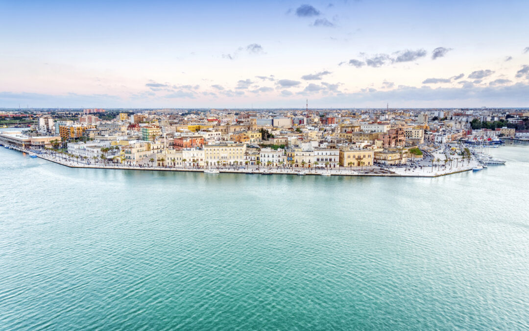 Ein malerischer Blick auf den Hafen von Brindisi bei Sonnenuntergang, mit Fischerbooten und historischen Gebäuden im Hintergrund.