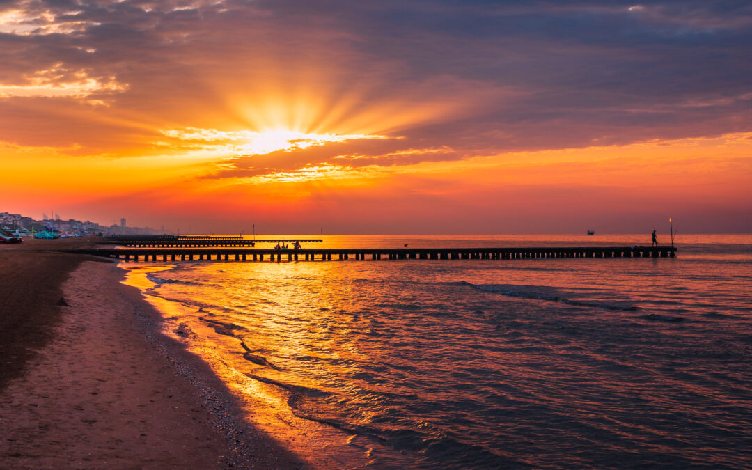 Sonnenuntergang am Lido di Jesolo mit goldenem Licht, das die ruhige See und den weiten Sandstrand erleuchtet.