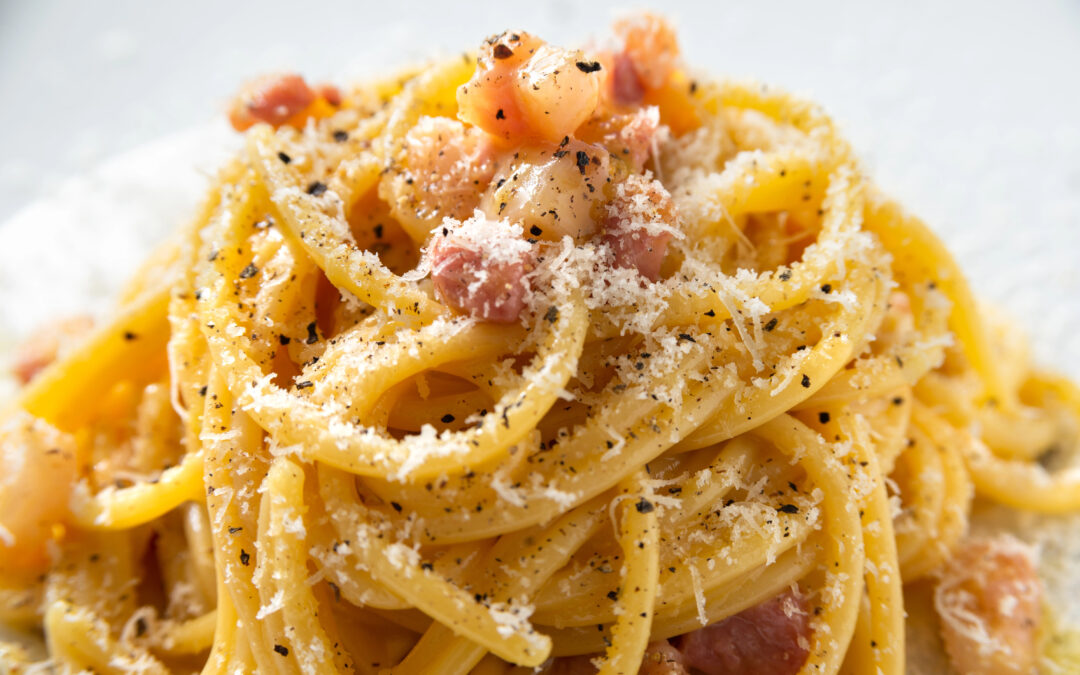 Nahaufnahme von Spaghetti alla Carbonara: Spaghetti in einer cremigen Eiersoße, garniert mit knusprigem Speck und frisch gemahlenem Pfeffer.