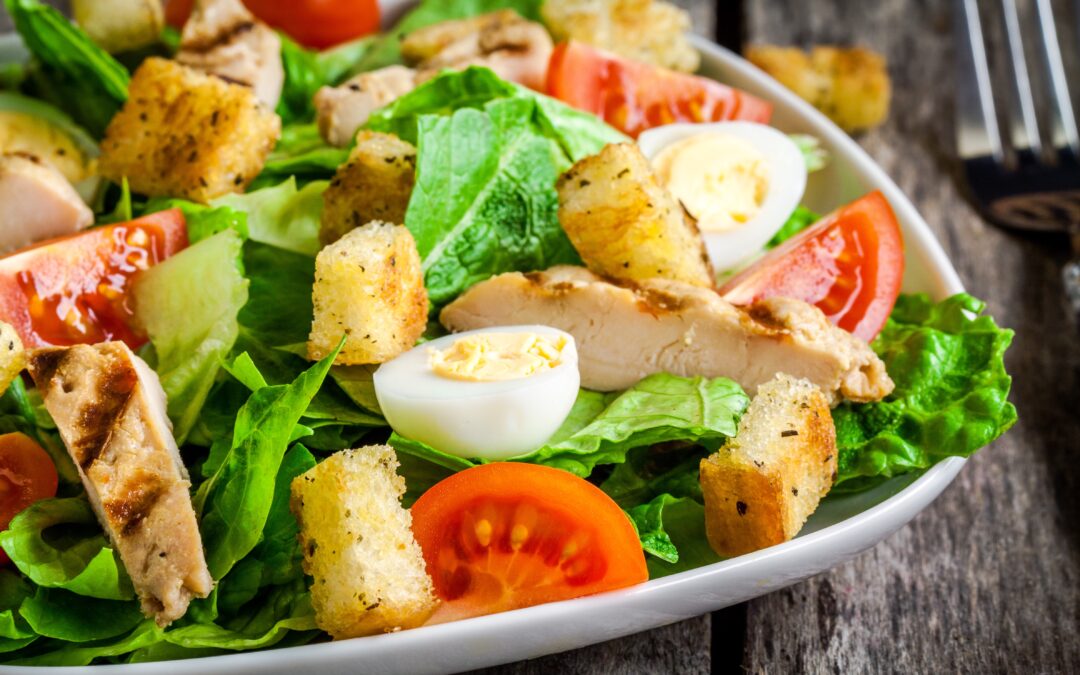 Eine rustikale Schüssel mit italienischem Brotsalat, bestehend aus knusprigen Brotstücken, reifen Tomaten, frischem Basilikum und roten Zwiebeln, angerichtet mit Olivenöl und Rotweinessig.