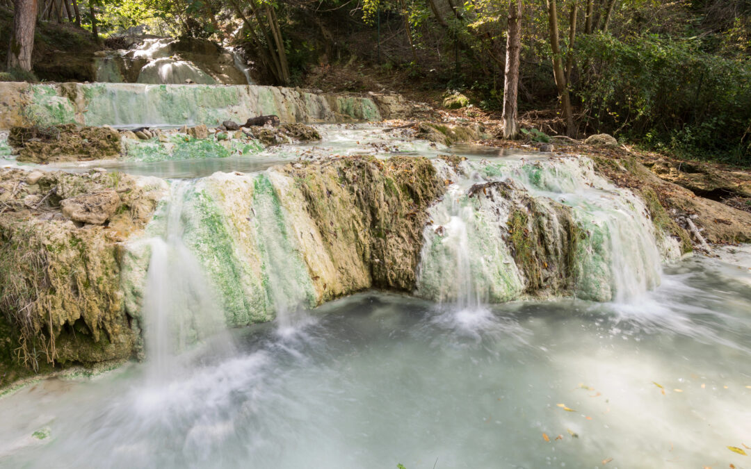 Eine malerische Ansicht der Thermalquellen von San Filippo ai Bagni, umgeben von grüner Natur.