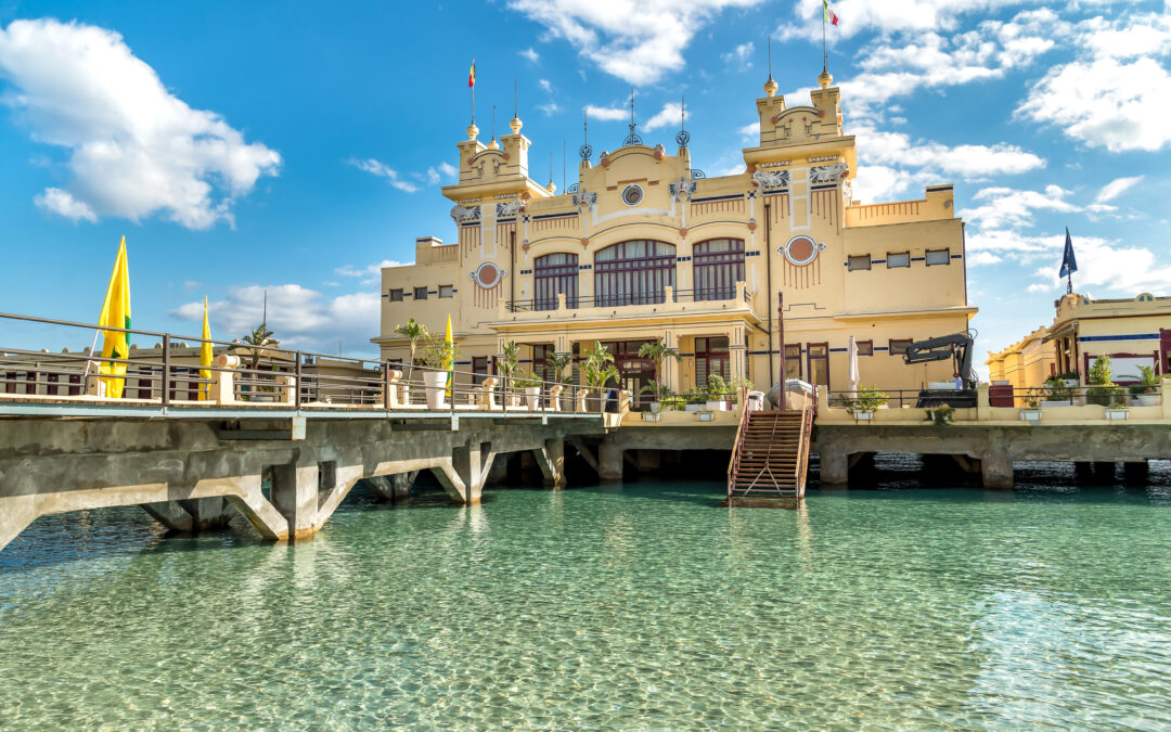 Das Charleston in Mondello, ein Jugendstilgebäude auf dem Meer, umgeben von kristallklarem Wasser und atemberaubender Küstenlandschaft.